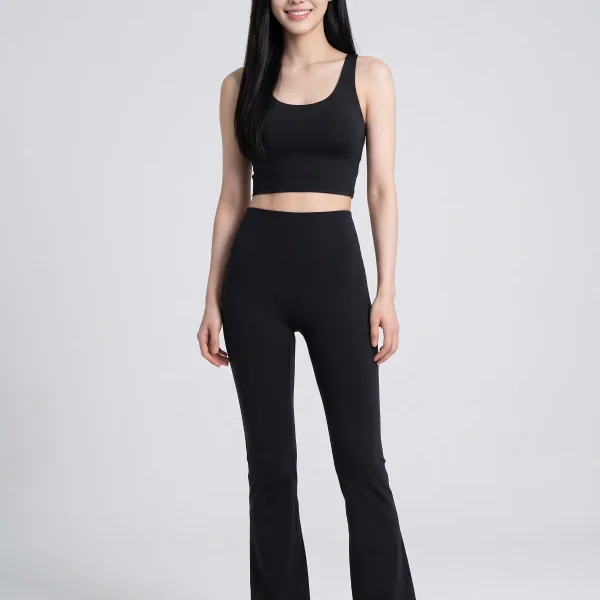 Black high-waisted flared yoga pants worn with a black crop top, standing